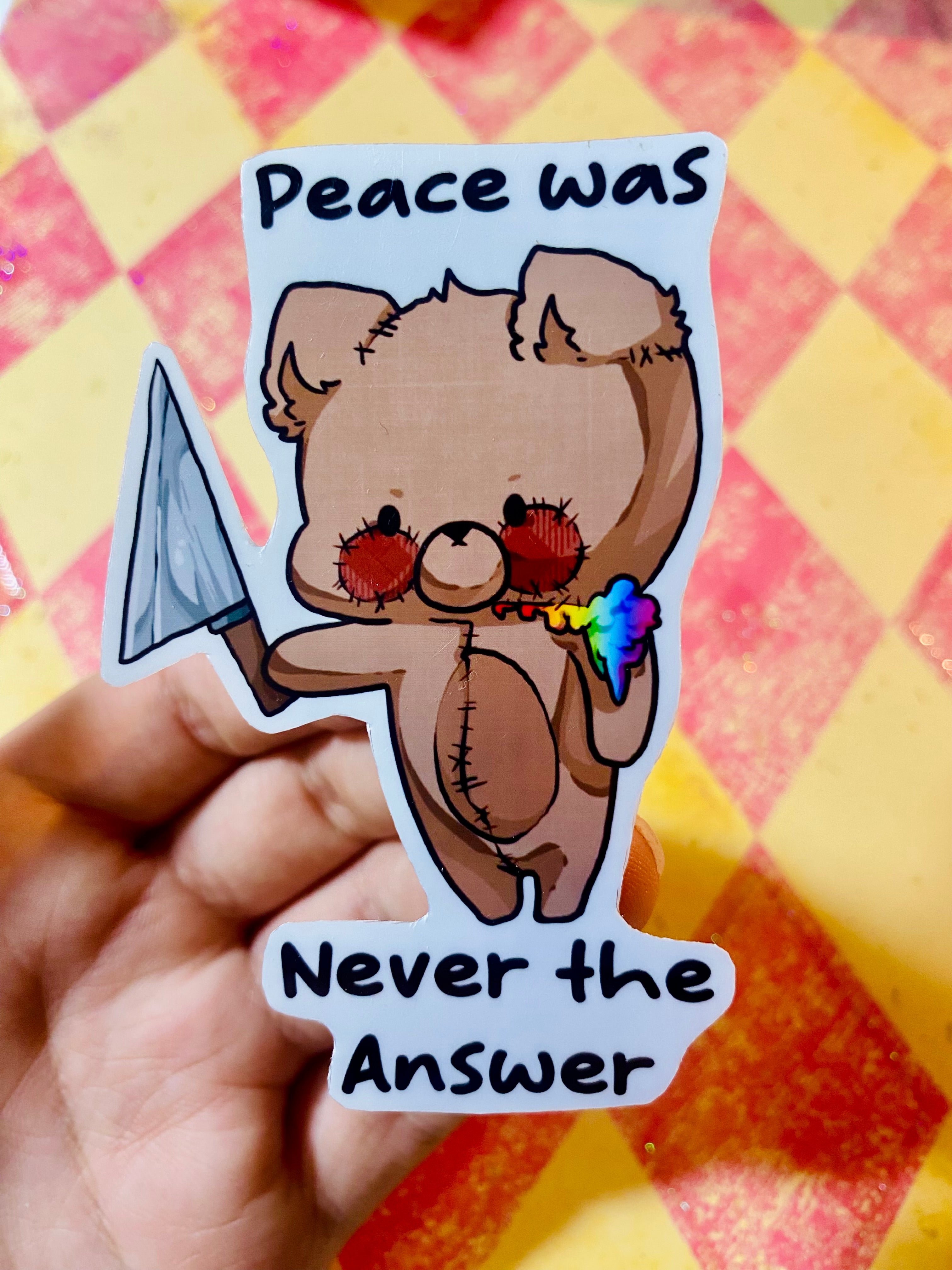 Sticker of a bear holding a knife, with text 'Peace was Never the Answer' on a checkered background.